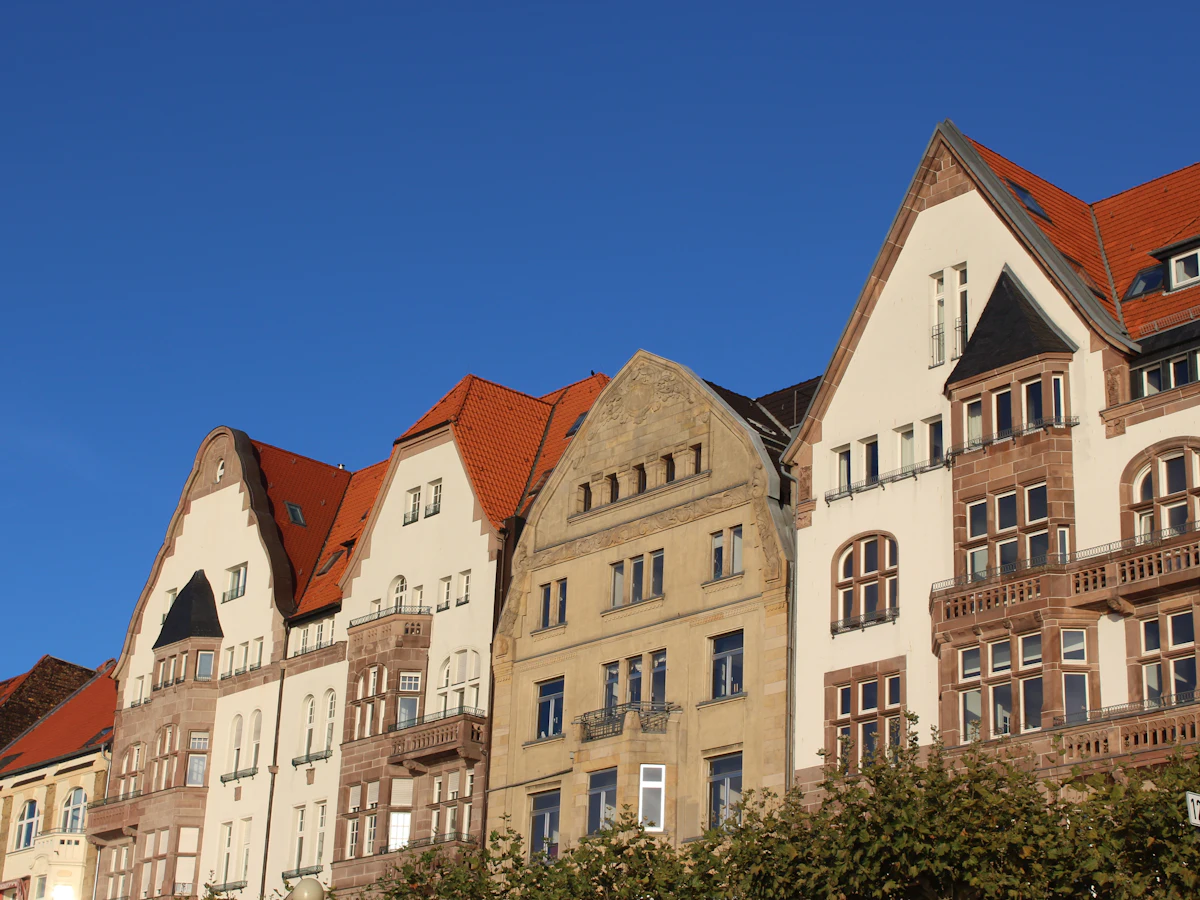 Sanierte Altbau-Wohnhäuser mit Giebeln vor blauem Himmel